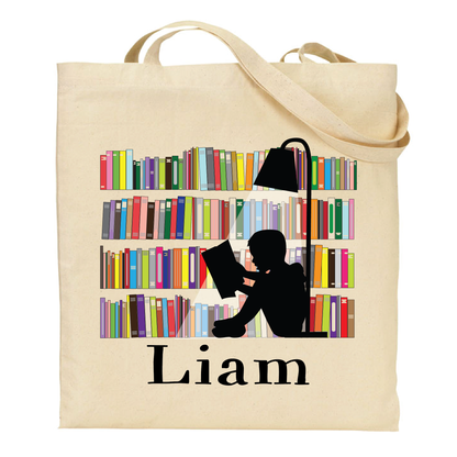 Beige tote bag with a design of a person reading a book in front of a bookshelf and the name 'Liam' on a white background.