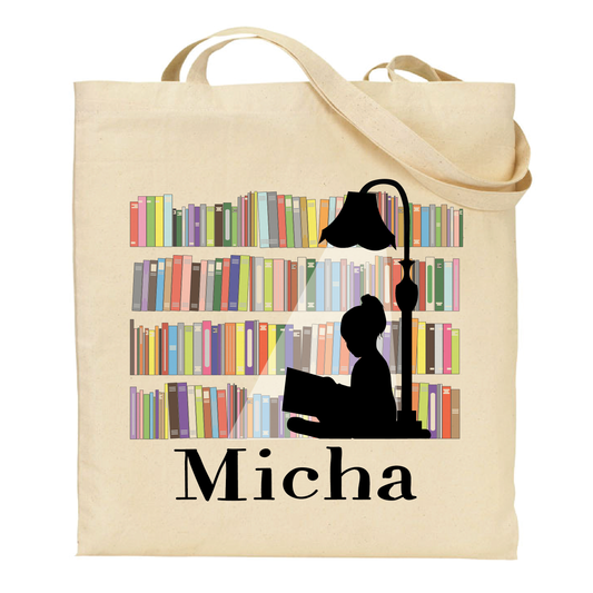 Beige tote bag with a silhouette of a person reading a book under a lamp, surrounded by books, and the name 'Micha' on a white background.