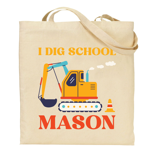 Beige tote bag with an excavator graphic and text 'I DIG SCHOOL' personalized with name