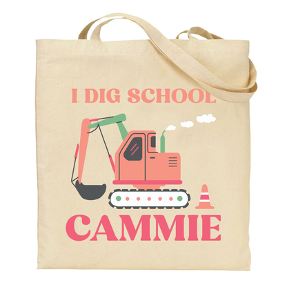 Beige tote bag with an excavator graphic and text 'I DIG SCHOOL' personalized with name